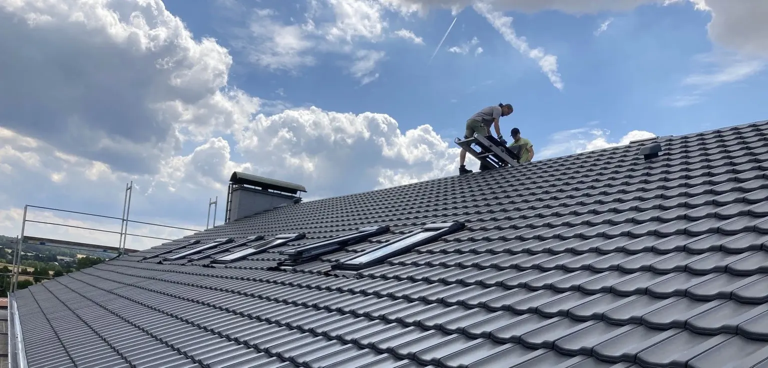 Dachdecker der Wunder Bedachungen GmbH bei der Arbeit auf einem neu eingedeckten Steildach mit Dachfenstern