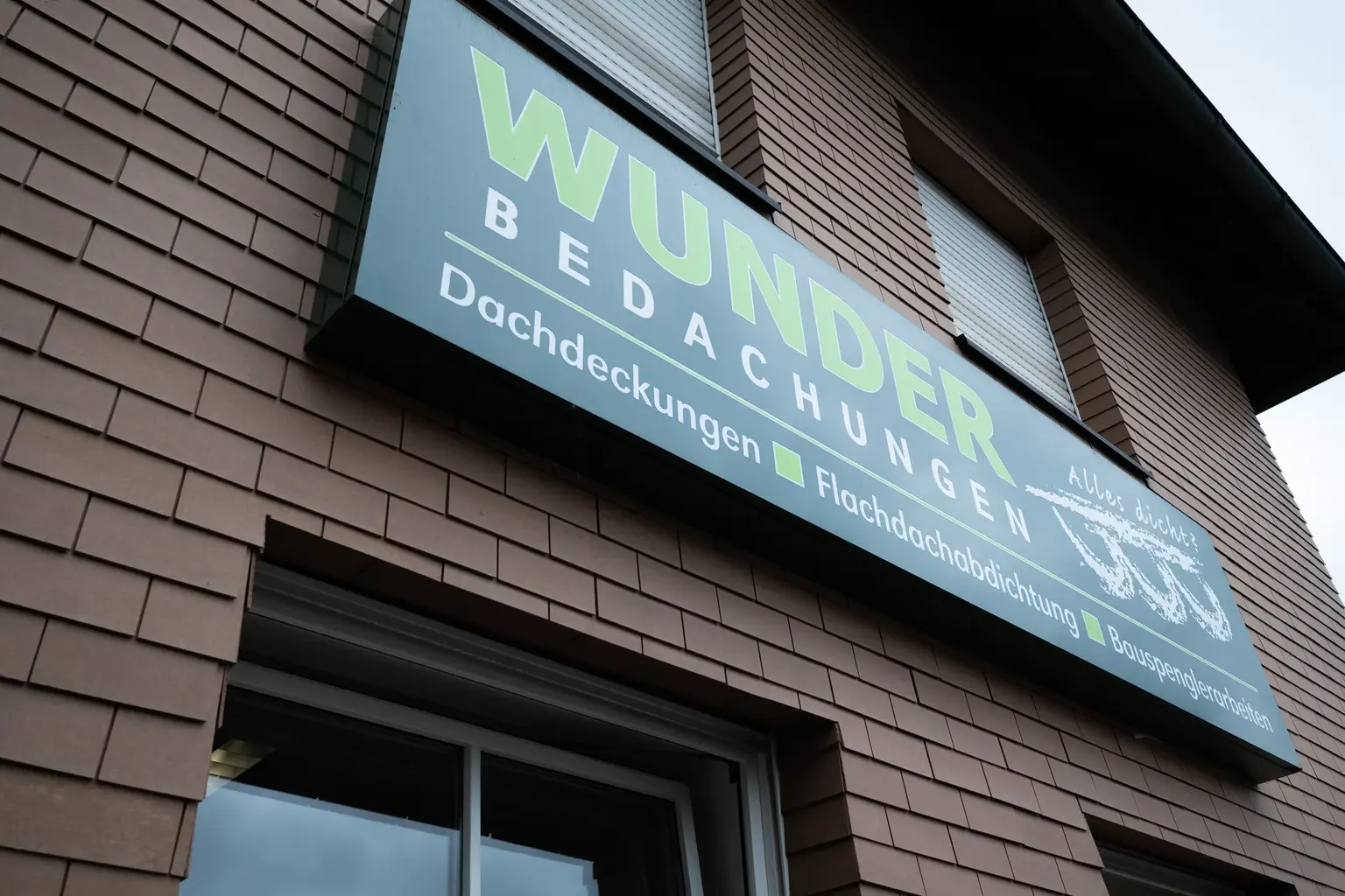 Firmenschild von Wunder Bedachungen am Betriebsgebäude in Coburg
